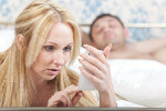 Woman Looking Through Man's Mobile Phone While He Is Asleep